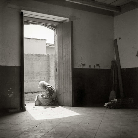 Anciana sentada en el umbral de la casa de un pueblo