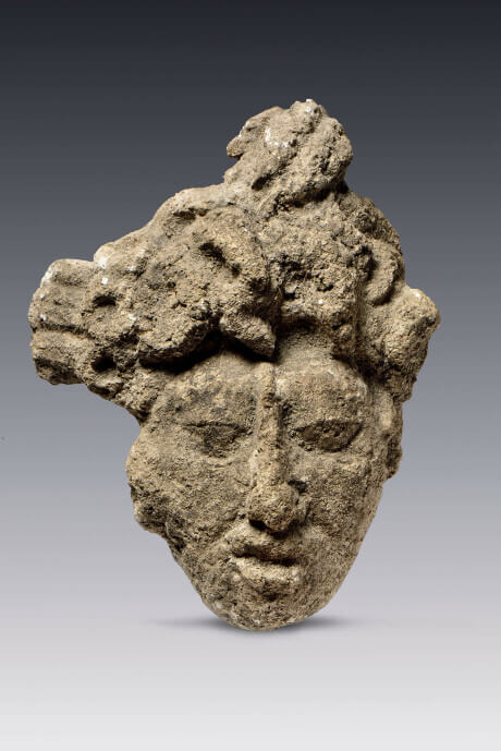 Cabeza de personaje esculpida en piedra con baño de estuco