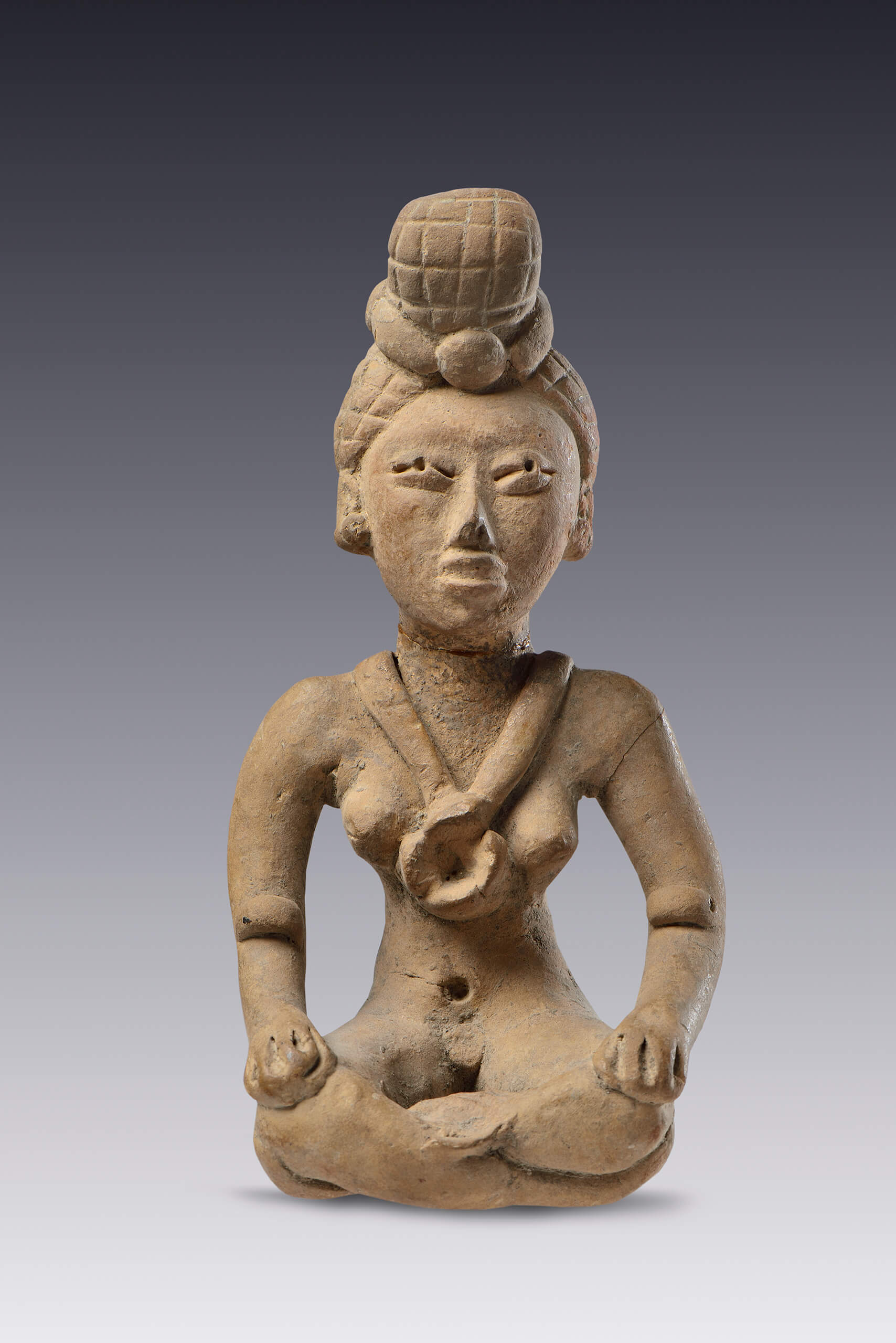 Figurilla de una mujer sentada con piernas cruzadas y un chongo  | El México antiguo. Salas de Arte Prehispánico | Museo Amparo, Puebla
