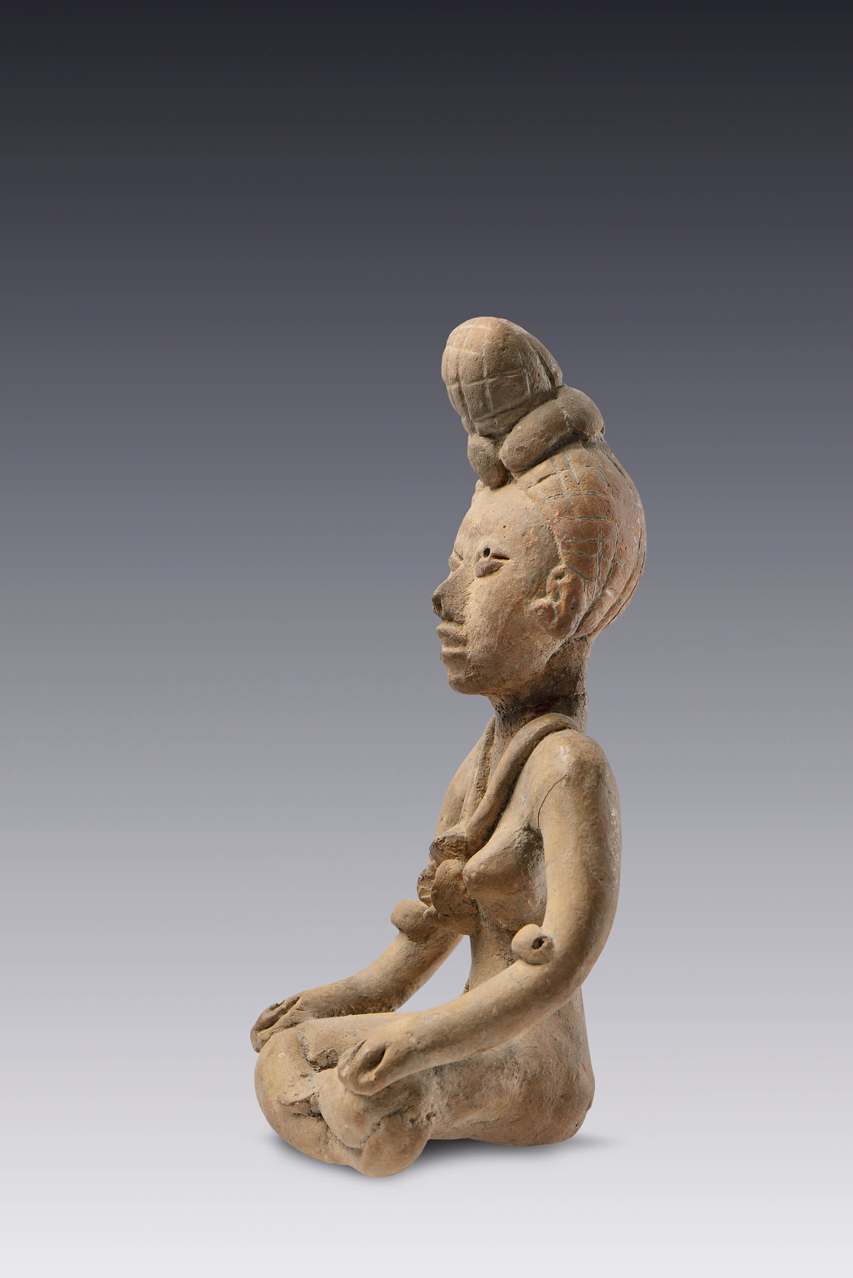 Figurilla de una mujer sentada con piernas cruzadas y un chongo  | El México antiguo. Salas de Arte Prehispánico | Museo Amparo, Puebla